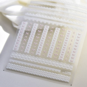 Macro detail of embossed nail art stickers featuring white lace and pink bows on TO-3493