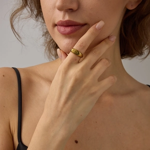 Gros plan d'une bague bombée en acier inoxydable doré portée à l'index par une femme