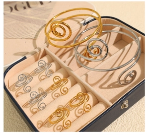 Detail view of gold and silver spiral rings and bracelets in a premium jewelry box