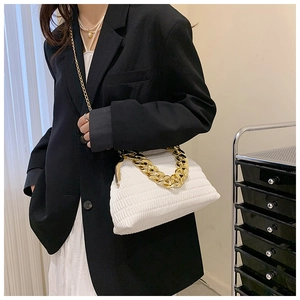 Sac à main blanc plissé avec une grosse chaîne dorée porté par un mannequin élégant