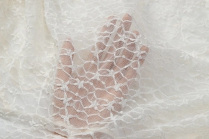 Gros plan sur la dentelle blanc cassé montrant les motifs ajourés et les détails du mesh