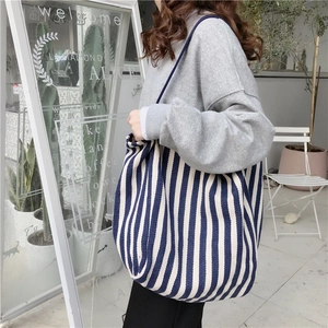 Chic blue and white striped canvas tote bag worn by a model in a minimalist store setting