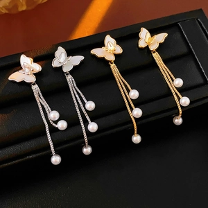 Vista detallada de pendientes de mariposa en oro y plata con perlas e incrustaciones
