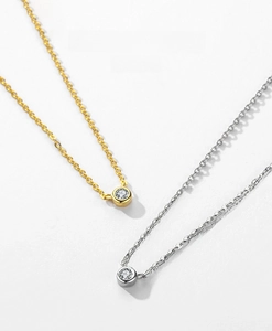 Detail of silver and gold necklaces with round-cut zircon pendants in bezel settings
