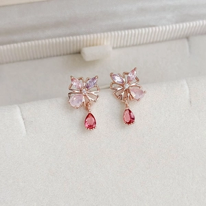 Macro shot of rose gold butterfly earrings with pink stones and red teardrop pendants