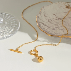 Detail of gold stainless steel necklace with spherical pendant and elegant T-bar closure