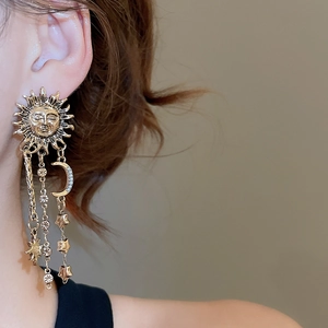 Detail view of vintage gold moon and star tassel earrings with celestial sun face design