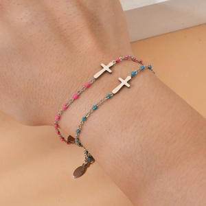Silver stainless steel cross bracelet set with pink and blue beads on a model wrist