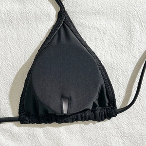 Detail of black bikini top showing inner pocket for removable pads and wave-textured elastic trim