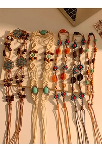 Détail de chaînes de taille tissées à la main avec perles en bois et pompons sur un livre