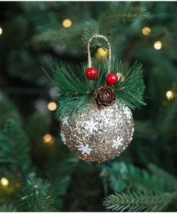 Close-up of golden glitter Christmas ball with white snowflakes and pine cone detail