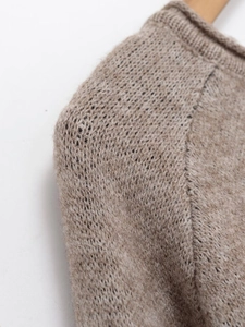 Detailed close-up of brown knit sweater texture with seamless raglan sleeve stitching