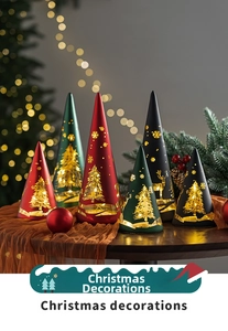 Detail of Christmas tree cone lanterns with warm LED patterns on an orange fabric table