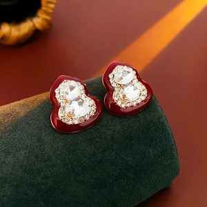 Detail of red enamel gourd earrings with crystal pavé and golden metal borders