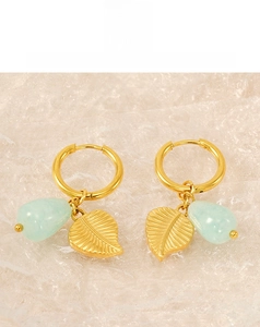 Détail macro du pendentif feuille en or 18k et perle bleue sur boucle en acier titane