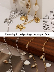 Macro detail of PVD gold plated necklace featuring crab and shell charms for beachwear