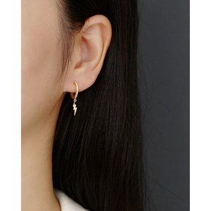 Detail of gold lightning bolt earrings with pavé crystals on a female model