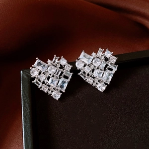 Close-up of heart-shaped silver stud earrings with sparkling cubic zirconia on brown silk