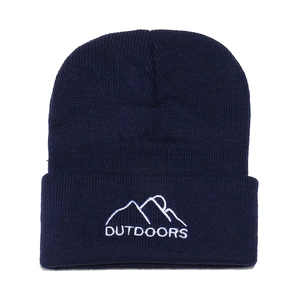Detailed close-up of dark blue knit beanie with white mountain embroidery and OUTDOORS text