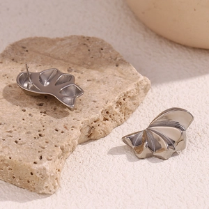 Detailed view of polished silver geometric petal earrings on natural stone texture