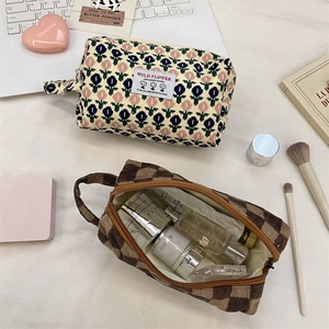 Flat lay of corduroy cosmetic bags in floral and checkerboard patterns on a white desk