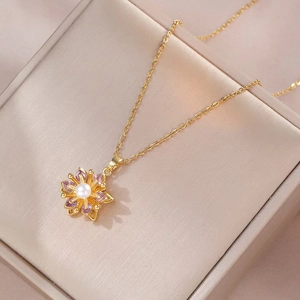 Drehbare Blumenkette in Goldoptik mit lila Edelsteinen und weißer Perle im Schmuckkästchen