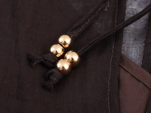 Macro detail of dark brown chiffon dress fabric with gold bead drawstring accents
