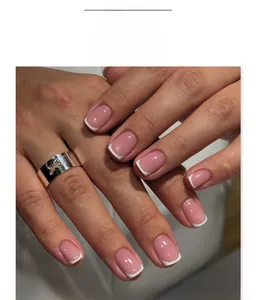 Close-up of classic French tip press-on nails with a silver hollow butterfly ring accent