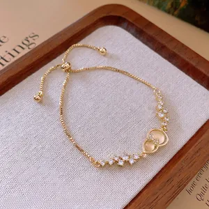 Gold zircon hulu bracelet with cat-eye stones and crystal bowknot on a wooden tray