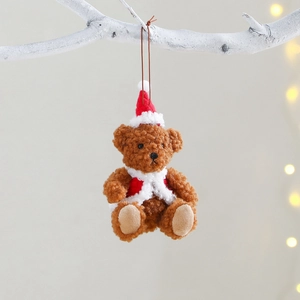 Christmas plush bear ornament wearing red Santa hat and vest hanging on a white branch