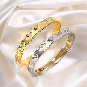 Titanium steel hollow heart bangles with crystals in gold and silver on white silk