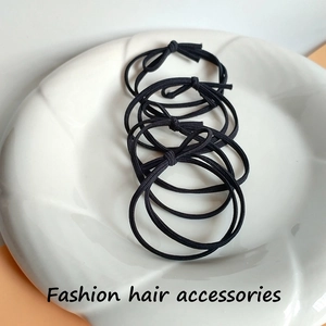 Close-up of four black high-elasticity hair ties with knot detail on a white dish