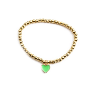 Elastic gold bead bracelet with green enamel heart pendant on a white background