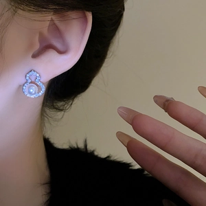 Close-up of silver gourd earrings with cubic zirconia and pearl on a model's ear