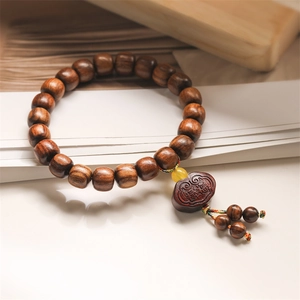 Detail view of dark wooden Buddhist prayer bracelet with Ruyi pendant and Fu character