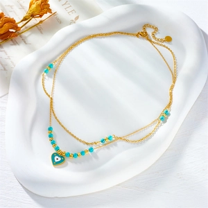 Detail of gold double-layered necklace with blue heart pendant on a white tray