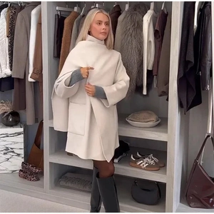 Detail of oatmeal oversized wool coat featuring large pockets and scarf-style high collar