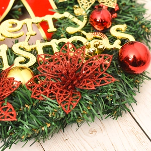 Detail of Christmas wreath featuring red poinsettia and golden Merry Christmas sign