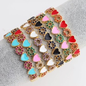 Colorful zircon heart charm bracelets in gold finish displayed on a velvet jewelry stand
