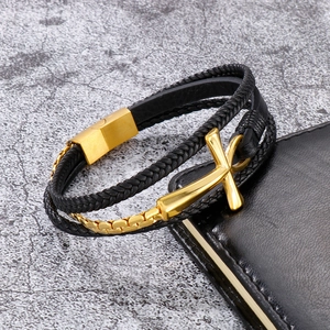 Detailed close-up of multilayer black leather bracelet with gold cross and magnetic clasp