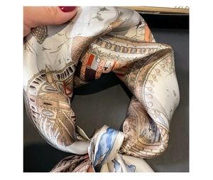 Detail of a silk scarf showing architectural prints with clocks and domes in a knot