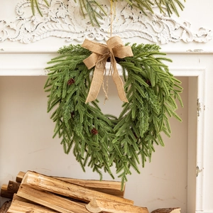 Détail d'une couronne de pins avec nœud en toile de jute et pommes de pin sur cheminée