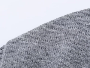 Gros plan sur la texture du tricot gris avec coutures fines et matière en laine douce