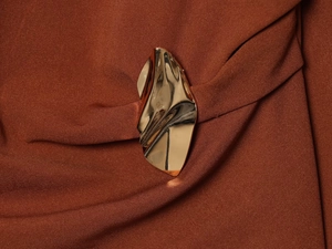 Detail of elegant gold buckle fastener on brown textured fabric of a chic outfit