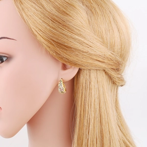 Close-up of gold-plated huggie earrings with colorful zircon stones on a model