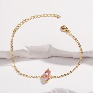 Close-up of golden heart bracelet with pink marquise stone and lobster clasp closure