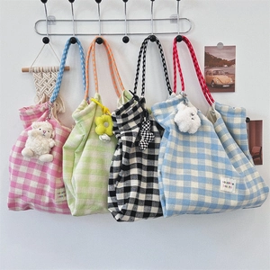 Detail of four plaid canvas tote bags with woven rope handles and cute plush charms