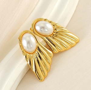 Macro shot of 18K gold-plated fan-shaped earrings with large oval pearls and ribbed texture