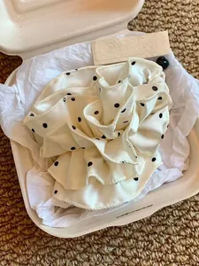 Gros plan d'un chouchou à pois crème en forme de rose dans une boîte cadeau élégante