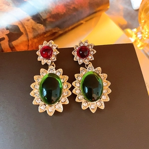 Detailed shot of retro gold earrings with red and green gemstones and rhinestones
